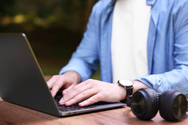 Dışarıdaki tahta masada dizüstü bilgisayarla çalışan Freelancer, yakın plan. Uzak görev