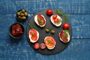 Lezzetli bruschettalar, ricotta peyniri, domates, dereotu ve zeytin mavi ahşap masa, düz uzanmış