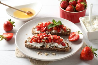 Ricotta peyniri, doğranmış çilek ve beyaz ahşap masada nane şekeri, yakın plan.