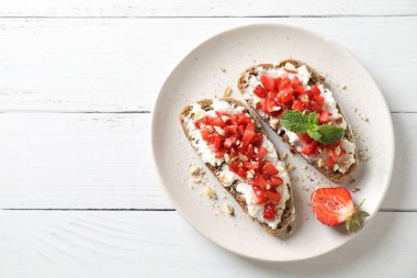 Ricotta peyniri, doğranmış çilek ve beyaz ahşap masada nane şekeri, üst manzara. Metin için boşluk
