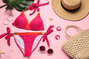 Pembe arka planda güzel mayo, şapka ve çanta ile düz kompozisyon
