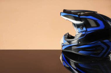 Ayna yüzeyinde bej arka planda güneşliği olan modern motosiklet kaskı. Metin için boşluk