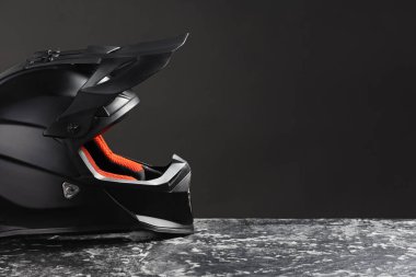 Gri taş yüzeyinde siyah arka planda güneşliği olan modern motosiklet kaskı. Metin için boşluk