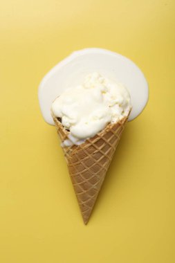 Sarı arka planda, dondurma külahında eritilmiş dondurma.