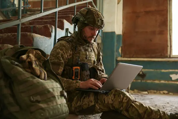 stock image Military mission. Soldier in uniform using laptop inside abandoned building