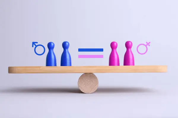 stock image Wooden balance scales with pawns showing concept of equality between men and women