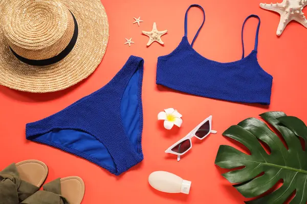 stock image Flat lay composition with blue swimsuit and sunglasses on coral background