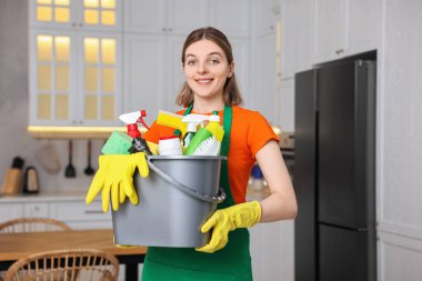 Temizlik işçisi mutfakta kova dolusu erzak tutuyor.