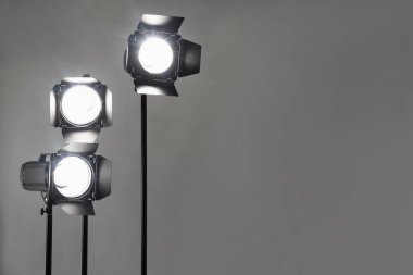 Gri fotoğraf arkaplanı ve profesyonel ışıklandırma ekipmanları stüdyoda. Metin için boşluk