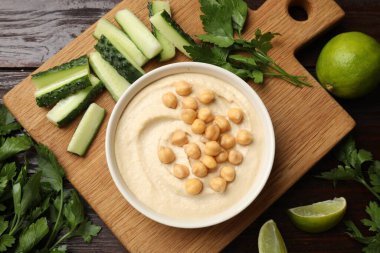 Lezzetli humus, kasede nohut ve ahşap masada taze ürünler.