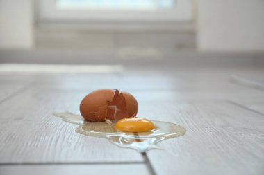 Açık ahşap zeminde kırılmış çiğ yumurta ve kabuk.