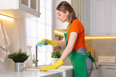 Mutfakta üniformalı temizlik malzemesi giyen profesyonel bir hademe.