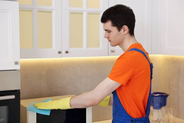 Mutfakta mikrodalga fırın temizleme üniforması giyen profesyonel bir hademe.