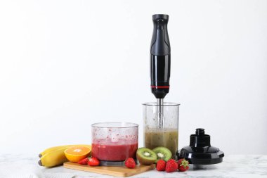 El blender seti, malzemelerin karışımı ve beyaz mermer masada taze meyveler.