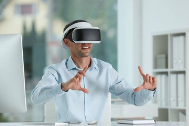 Gülümseyen adam ofiste sanal gerçeklik kulaklığı kullanıyor.