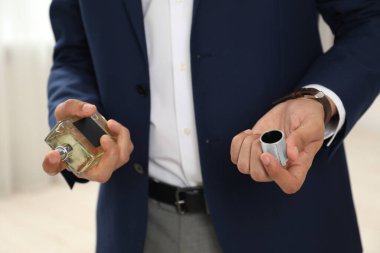 Genç adam evin içine lüks parfümler sıkıyor.