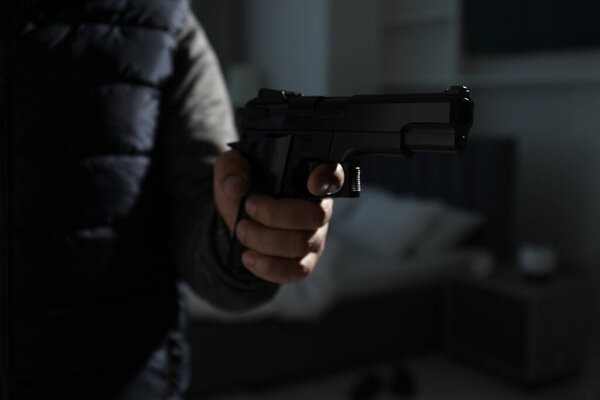 Dangerous criminal with gun in foreign house, closeup. Armed robbery