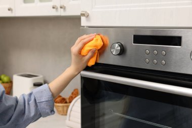 Kadın mutfakta, closeup bez ile elektrikli fırın Temizleme
