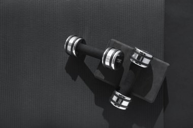 Dambıllar, yoga bloğu ve siyah arka planda minder, düz yatış. Metin için boşluk