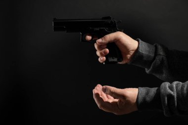 Siyah arka planda silahı olan tehlikeli bir suçlu, yakın plan. Silahlı soygun.