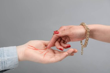 Fortune teller reading lines on woman's palm against light grey background, closeup. Chiromancy clipart