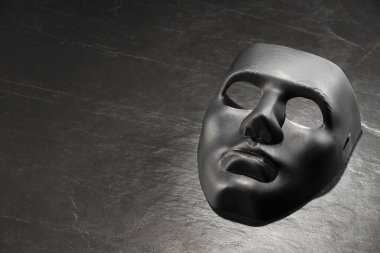 Siyah tahta yüzeyde plastik yüz maskesi, metin için boşluk. Tiyatro performansı