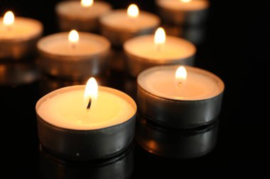 Siyah arkaplanda birçok yanan gece lambası mumu, yakın plan