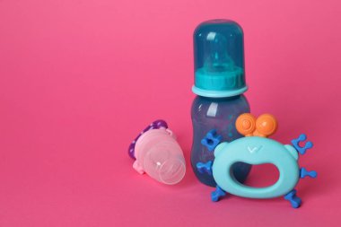 Kırmızı arka planda bebek çıngırağı, şişe ve kemirgen. Metin için boşluk