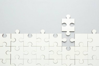 Gri arka planda beyaz yapboz parçaları, üst manzara. Metin için boşluk