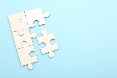 Açık mavi arka planda beyaz yapboz parçaları, üst manzara. Metin için boşluk