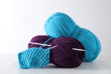 İplik derileri, örgü kumaş ve açık gri arka planda iğneler.