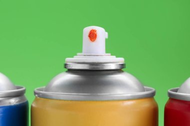 Birçok sprey boya kutusu yeşil arka planda, yakın plan