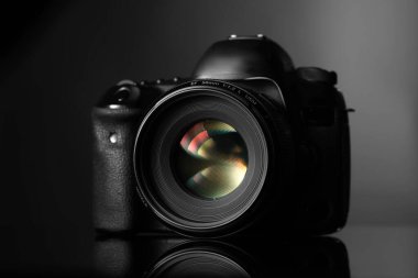 Siyah ayna yüzeyinde modern bir fotoğraf makinesi.