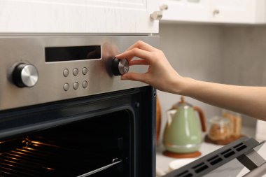 Mutfakta elektrikli fırın kullanan kadın, yakın plan.