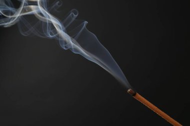 Siyah arka planda yanan tütsü çubuğu, yakın plan.