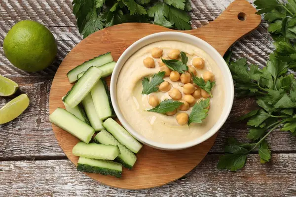 Lezzetli humus, kasede nohut ve ahşap masada taze ürünler.