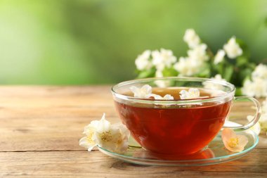 Sıcak yasemin çayı fincanda ve çiçekler ahşap masada, metin için yer