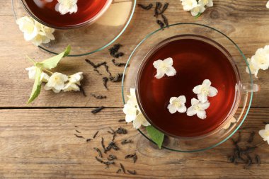 Sıcak yasemin çayı fincanda ve çiçekler ahşap masada, düz yatıyordu.