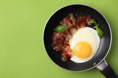 Kızarmış yumurta, pastırma ve fesleğen, yeşil arka planda, üst manzara. Metin için boşluk