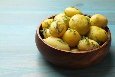 Açık mavi ahşap masada dereotlu kaynamış patatesler. Metin için boşluk