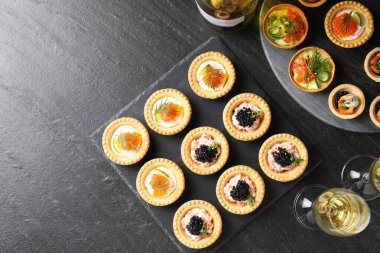 Lezzetli kanepeler ve siyah desenli masada beyaz şarap bardakları. Metin için boşluk