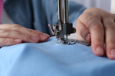 Terzi içeride dikiş makinesiyle çalışıyor, yakın plan.