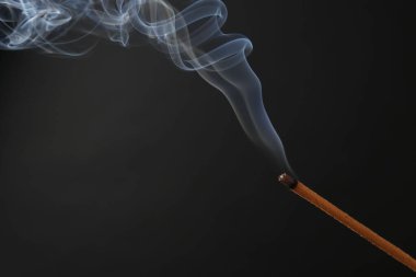 Siyah arka planda yanan tütsü çubuğu, yakın plan.