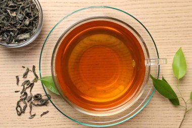 Yeşil çayı fincanda tazeleyip, ahşap masada yapraklar bırakarak, düz bir şekilde yatarak