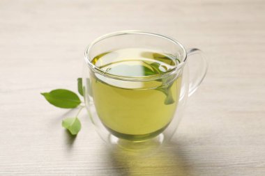 Yeşil çayı fincanda tazeleyen ve ahşap masada yapraklar, yakın plan