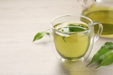 Yeşil çayı fincanda tazelemek, çaydanlık ve yaprakları ahşap masada, yakın plan. Metin için boşluk