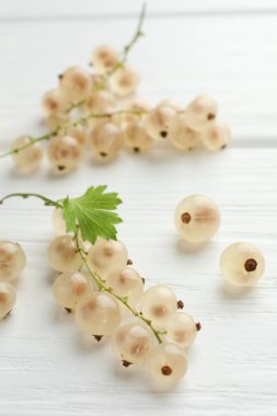 Taze kuşüzümü ve yeşil yaprak beyaz ahşap masada, yakın plan.