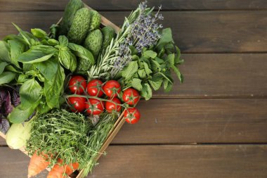 Tahta masadaki sandıkta farklı aromatik otlar ve sebzeler. Metin için boşluk