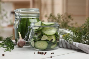 Ev yapımı turşu. Kavanozlardaki taze salatalıklar, biberlikler ve beyaz ahşap masadaki dereotlar, yakın plan.