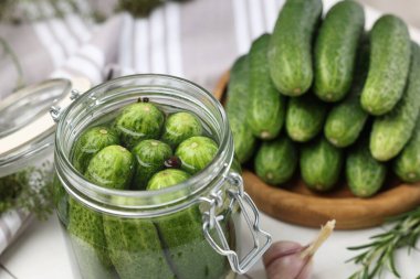 Kavanozda salatalık turşusu, beyaz masada, yakın plan.